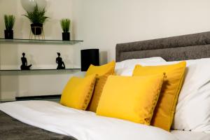 a pile of yellow pillows sitting on a bed at Boutique 2 Bedroom Apartment In Pontcanna Cardiff in Cardiff