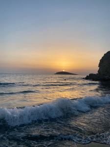 een zonsondergang over de oceaan met een eiland in de verte bij Happinest Private Apartment in Kalymnos