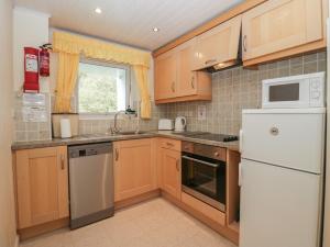 eine Küche mit Holzschränken und einem weißen Kühlschrank in der Unterkunft Apartment 3 in Keswick