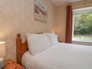ein Schlafzimmer mit einem weißen Bett und einem Fenster in der Unterkunft Apartment 3 in Keswick