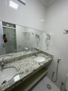 ein Badezimmer mit zwei Waschbecken und einem großen Spiegel in der Unterkunft Spazzio diRoma 2024 - COM CAFÉ DA MANHÃ in Caldas Novas