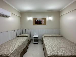a room with three beds and a tv on the wall at Spazzio diRoma 2024 - COM CAFÉ DA MANHÃ in Caldas Novas