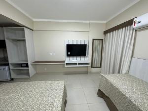a bedroom with two beds and a flat screen tv at Spazzio diRoma 2024 - COM CAFÉ DA MANHÃ in Caldas Novas
