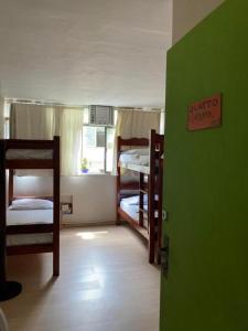 a room with three bunk beds and a green door at Hostel New Ipanema in Rio de Janeiro