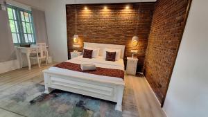 um quarto com uma cama branca e uma parede de tijolos em Kandalama Lodge em Dambulla