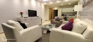 un soggiorno con 2 sedie bianche e una TV di Appartement Radia a El Jadida