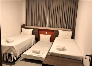 2 camas individuales en una habitación con ventana en 2 DORMITÓRIOS FRENTE AO THERMAS DOS LARANJAIS en Olímpia