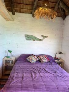 een slaapkamer met een paars bed en een kroonluchter bij Palapa Suite in Punta Del Diablo