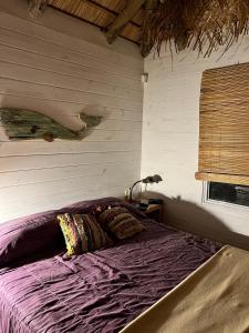een paars bed in een kamer met een raam bij Palapa Suite in Punta Del Diablo