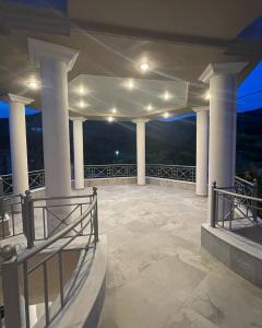 une grande terrasse avec colonnes et lumières la nuit dans l'établissement Staikos, à Ligia