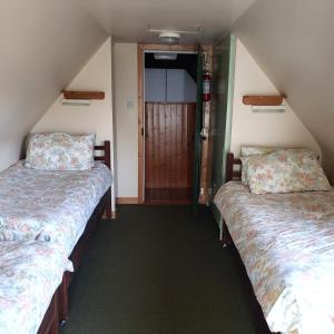2 łóżka pojedyncze w pokoju z drzwiami w obiekcie Traditional Cosy Cottage w mieście Louisburgh