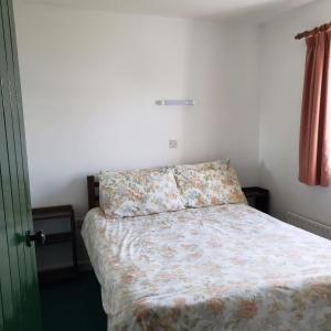 a bedroom with a bed with a floral bedspread at Traditional Cosy Cottage in Louisburgh