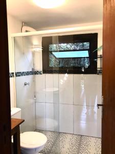 a bathroom with a toilet and a glass shower at Pescador de Sonhos in Praia do Rosa