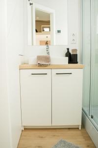 a white bathroom with a sink and a mirror at Tiny Om Ferienhaus in Laichingen