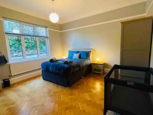 a bedroom with a bed with a blue comforter and two windows at Gorwel is an Art Deco 1930s villa with sea views in Deganwy