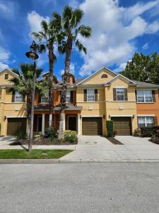 une grande maison jaune avec des palmiers et un éclairage de rue dans l'établissement Theme Park Gateway!, à Kissimmee