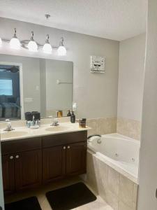 a bathroom with a sink and a tub and a mirror at Theme Park Gateway! in Kissimmee