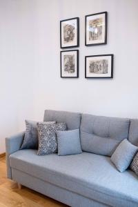 eine blaue Couch in einem Wohnzimmer mit Bildern an der Wand in der Unterkunft Old Town Zamkowa vis a vis Wawelu in Krakau