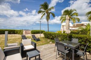 a patio with chairs and an umbrella and the ocean at Baie Nettle Beach Villa 1130 in Saint Martin
