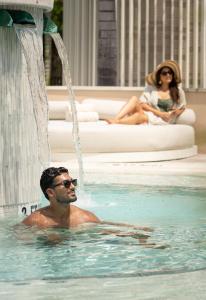 un uomo in una piscina con una fontana di The Ritz-Carlton Orlando, Grande Lakes a Orlando