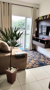un soggiorno con divano e pianta in vaso di Apartamento com piscina churrasqueira em Ubatuba a Ubatuba