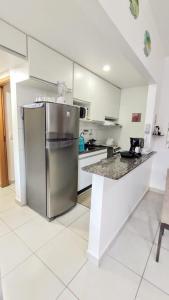 uma cozinha com um frigorífico de aço inoxidável e um balcão em Apartamento com piscina churrasqueira em Ubatuba em Ubatuba mais 39 fotografias