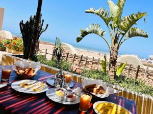a table with food and a view of the beach at Dar Afoulky Maison D'hotes in Sidi Kaouki