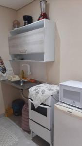 a small kitchen with a sink and a microwave at Kitinet Central in Belo Horizonte