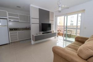 een keuken en een woonkamer met een bank en een televisie bij 449 - Lindo Apartamento de 3 dormitórios á 80m da praia de Bombas in Bombinhas