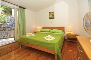 a bedroom with a green bed and a window at Apartmani Katarina in Hvar