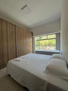 um quarto com uma grande cama branca e uma janela em Suites Silva em Capitólio