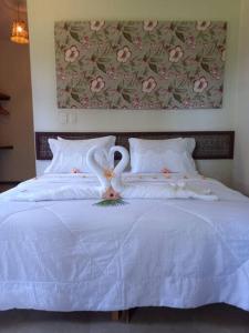 ジャパラティンガにあるMaravilhoso chalé num paraíso em Japaratingaの白いベッドに白鳥2羽が備わるベッドルーム1室