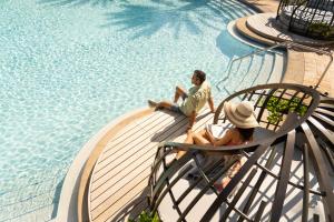 two people sitting in chairs by a swimming pool at The Ritz-Carlton Orlando, Grande Lakes in Orlando
