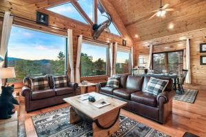 a living room with leather furniture and large windows at Epic Mountain Views, Hot Tub, Game Room, Sleeps 10 in Sevierville