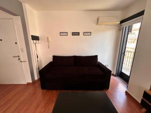 - un salon avec un canapé noir et une fenêtre dans l'établissement Apartamento en Las Cañitas, à Buenos Aires