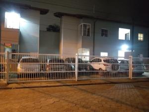 a fence with cars parked in front of a building at Cantinho do sossego na praia grande Ubatuba in Ubatuba