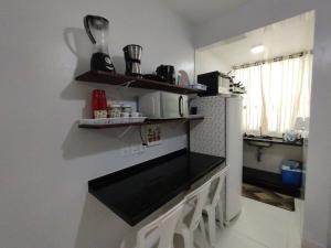 a kitchen with a counter with a refrigerator and shelves at Cantinho do sossego na praia grande Ubatuba in Ubatuba