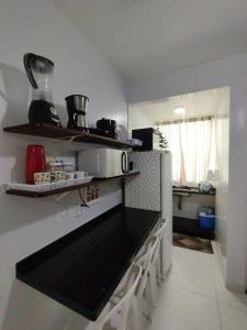 a kitchen with a counter and a microwave on a wall at Cantinho do sossego na praia grande Ubatuba in Ubatuba