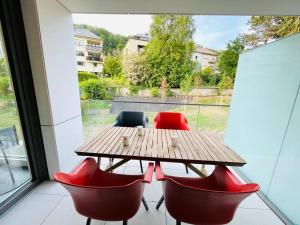 een houten tafel en rode stoelen op een balkon bij Luxury Green Flat in Center in Luxemburg