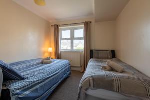 a bedroom with two beds and a window at 13 Victoria Road Apartment in Cardiff