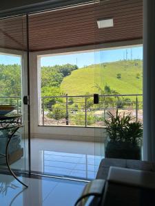 a living room with a view of a hill through a window at Suites Silva in Capitólio