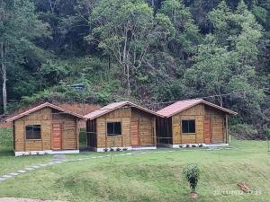 eine Holzhütte auf einem Feld neben einem Wald in der Unterkunft Chalés Maravilha 05 in Alfredo Chaves