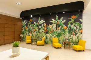 a wall with a mural of flowers and yellow chairs at Hotel Catalinas Tucuman in San Miguel de Tucumán