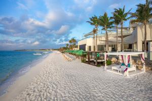 a beach with chairs and a building and the ocean at The Sens Tulum Riviera by Oasis in Akumal