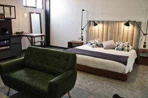 ein Schlafzimmer mit einem Bett und einem grünen Stuhl in der Unterkunft Loft cobalto en excelente ubicación! in San Luis Potosí