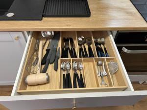 a wooden drawer filled with utensils on a counter at Apartman G6 in Bjelovar