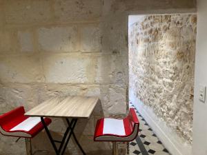 uma mesa e duas cadeiras em frente a uma parede de pedra em Maison au cœur de la Ville. em Saint-Gilles