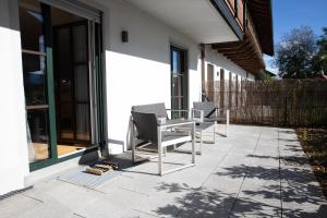 un patio con 2 sillas y una mesa en una casa en Gutshof Alpenblick am Simssee - über den man spricht, en Stephanskirchen