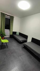 a room with two beds and a green chair at Apartmány u golfu in Jihlava