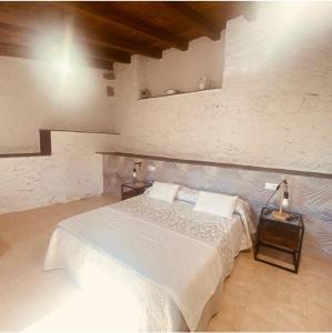 um quarto com uma cama branca e duas mesas em Terriña Salvaxe em Quiroga